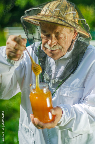 senior apiarist checking his honey in apiary