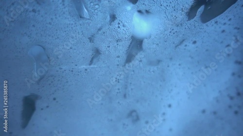 Foam flows down the glass with splash in super slow motion.