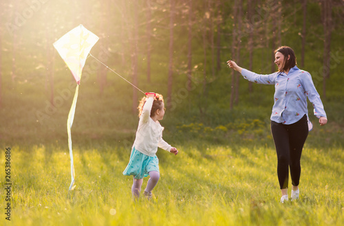 Slika na platnu sweet little girl running with kite at the sunny meadow,mothers watchin