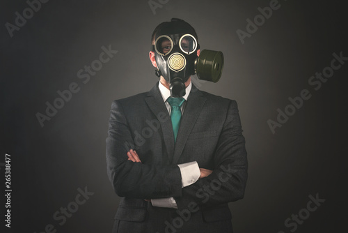 Disgruntled man in a gas mask and suit on a gray background. Pollution of environment concept. © Dmitriy