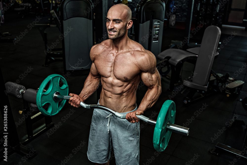 Young handsome sportsman bodybuilder weightlifter with an ideal body, after coaching poses in front of the camera, abdominal muscles, biceps triceps. In sportswear. Young handsome sportsman bodybuilder weightlifter with an ideal body, after coaching poses in front of the camera, abdominal muscles, biceps triceps. In sportswear.