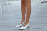 White fashionable shoes on beautiful female tanned legs on a wooden background