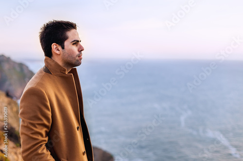 Profile of a guy with a stylish hair and beige coat standing on