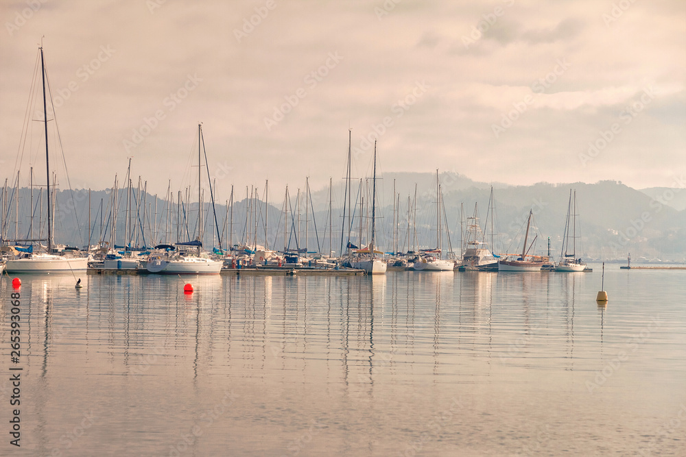 gulf of ligurian coast on background of Alps mountains with yachts and embankment of the city of La Spezia in Italy in pink dawn