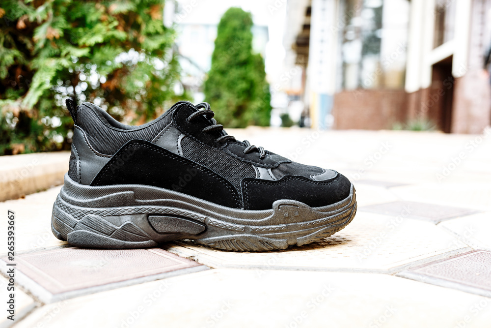 black sneakers on thick black soles against the background of paving slabs black sneakers on thick black soles against the background of paving slabs