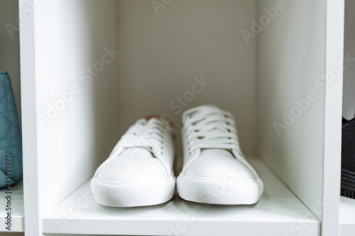 pair of white sneakers on the white shelf in the store