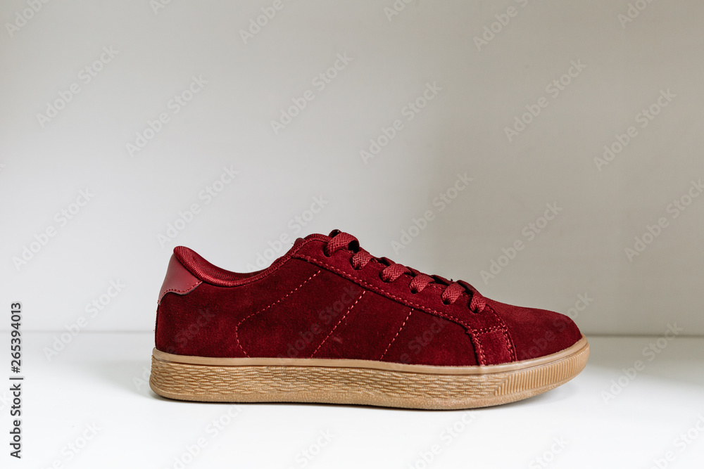 burgundy suede sneaker on a beige sole and on a white shelf in the store burgundy suede sneaker on a beige sole and on a white shelf in the store
