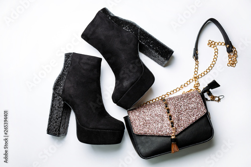 black suede ankle boots on a platform and thick heels with sparkles and a black bag with sparkles on the flap on a white background