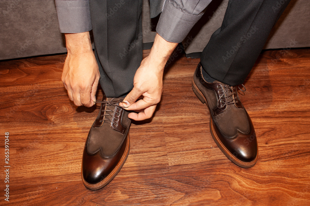 Man adjusting shoelaces before getting up to walk Man adjusting shoelaces before getting up to walk