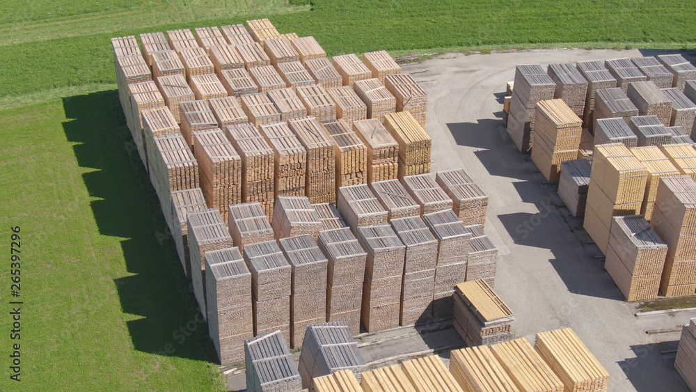 Fototapeta premium AERIAL: Flying above a neatly organized lumberyard in sunny Austrian countryside