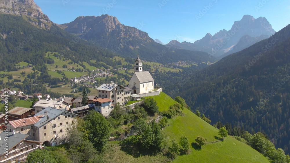 DRONE: Flying over a church and a small graveyard on top of a hill in Dolomites.