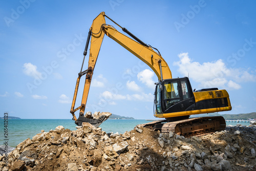 backhoe loader digger excavator stone working construction site on the beach sea ocean