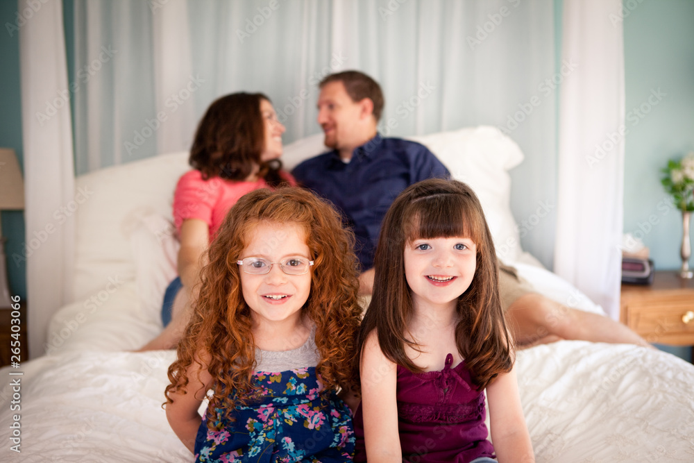 Happy Family Sitting on Bed in Bedroom at Home Happy Family Sitting on Bed in Bedroom at Home