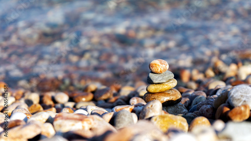 pyramid of stones on the colorful cover of pebbles on the beach with crystal clear water 2