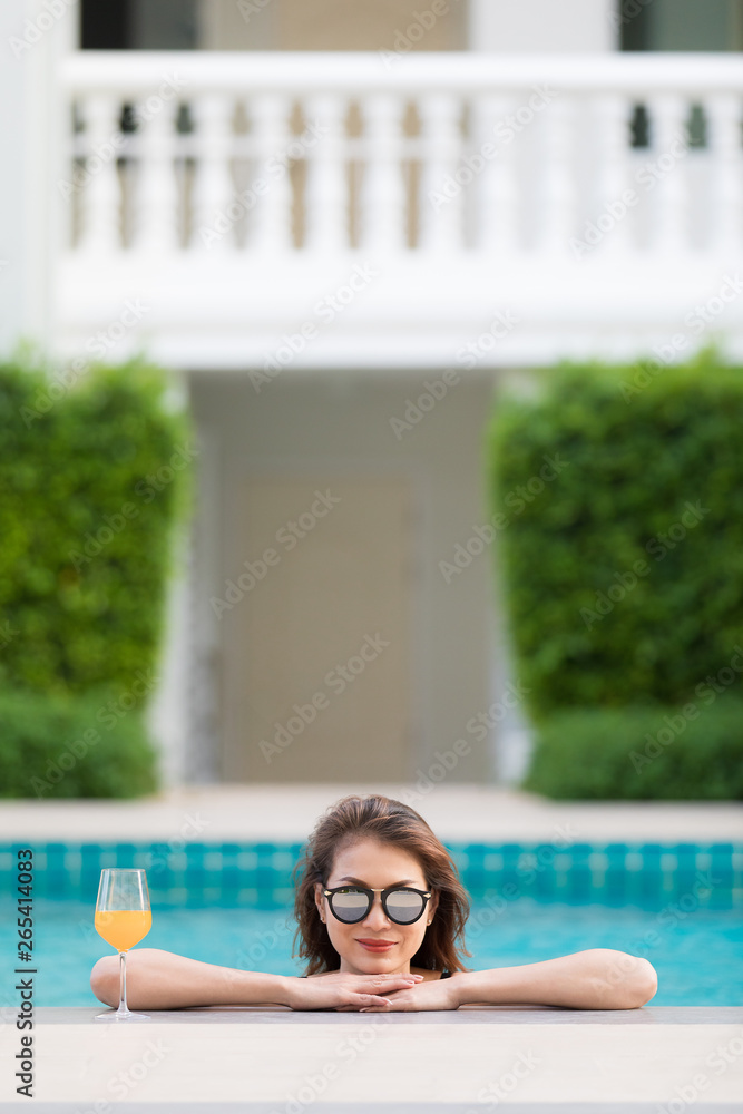 Asian woman in pool with glass of orange juice