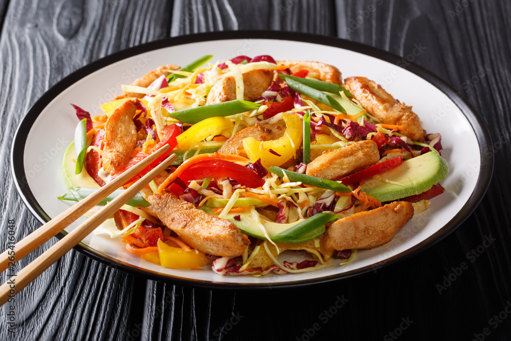 Colorful healthy asian cabbage salad with chicken, avocado and vegetables close-up on a plate. horizontal Colorful healthy asian cabbage salad with chicken, avocado and vegetables close-up on a plate. horizontal