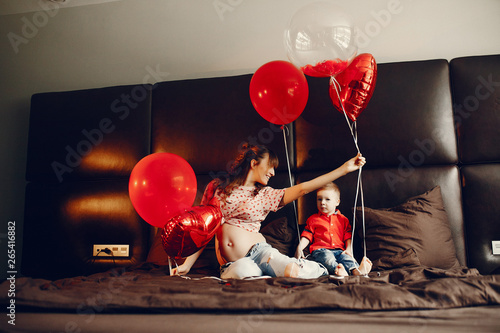 Pregnant woman at home. Mother with son in a bed. Family in a room with decorstions for Valentine's day photo