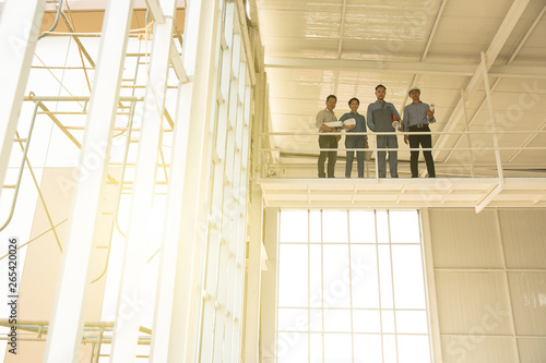 Group of engineers, man and woman, working together in construction site, standing on bridge among the scarfold photo