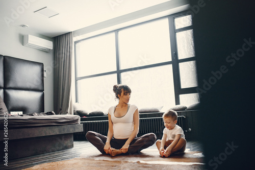 Pregnant woman at home. Mother with son doing yoga. Family in a room with large windows