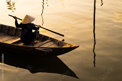 Vietnamese woman in traditional bamboo hat rowing