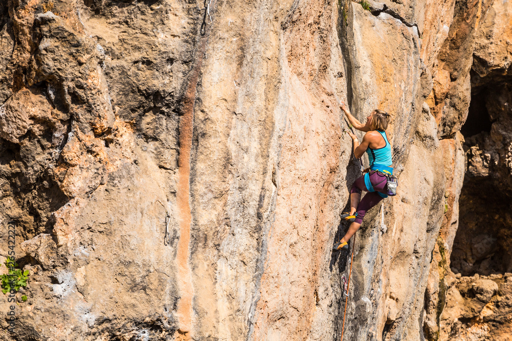 Fototapeta premium A girl climbs a rock.