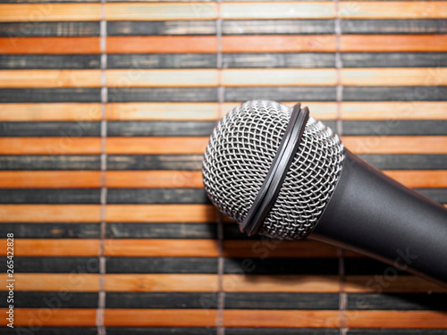 Top-Down View of A Microphone Head and Silver Grille on A Striped Yellow and Black Bamboo Mat Background. Karaoke Bar, Party Concept. Copy Space.