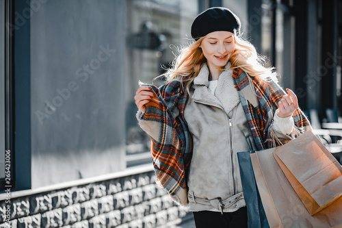 Elegant lady in a winter city. Stylish girl walking with shopping bags. Blonde in a cute beret
