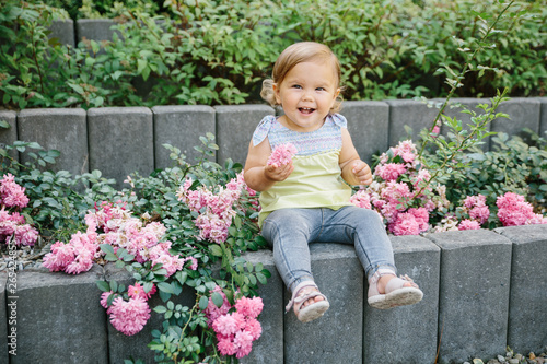 Baby girl outside playground laughing in flowers