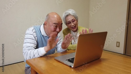 パソコンの画面に手を振るおじいちゃんとおばあちゃん