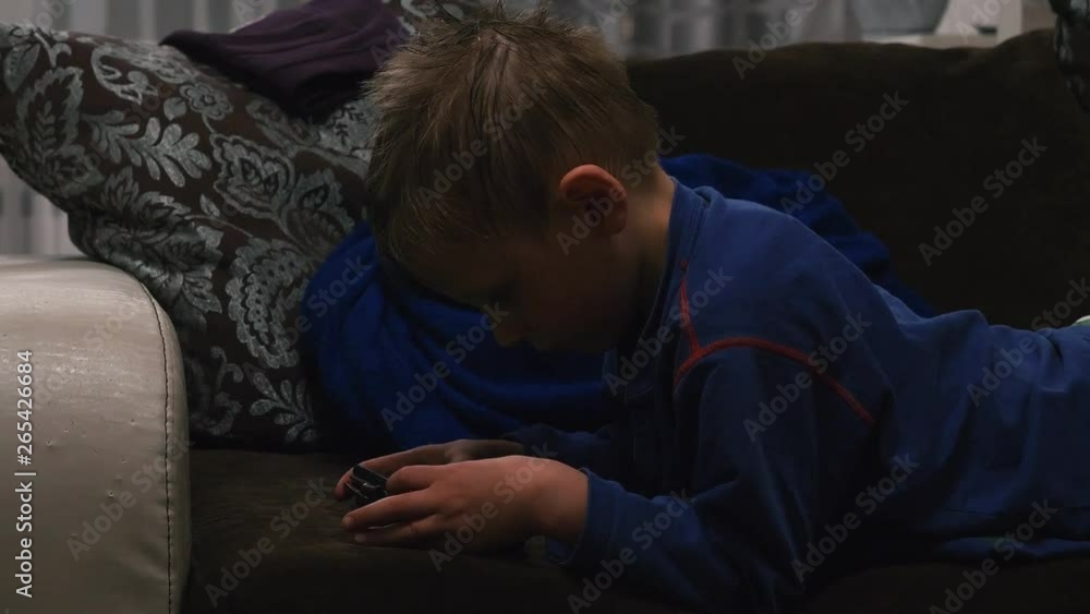 boy playing in the phone while lying on the couch boy playing in the phone while lying on the couch
