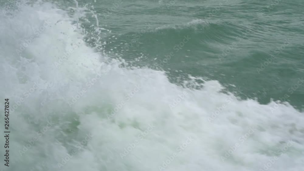 Blue ocean sea water wave with fast yacht boat wake foam of prop wash. Close up, Thailand. Splashes of sea water during the movement of the ship. Concept of travel and nature Blue ocean sea water wave with fast yacht boat wake foam of prop wash. Close up, Thailand. Splashes of sea water during the movement of the ship. Concept of travel and nature