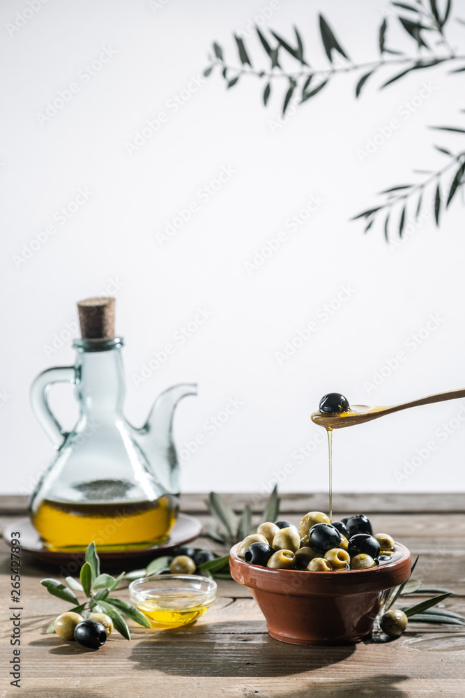 Olive oil and olive branch on the wooden table Olive oil and olive branch on the wooden table