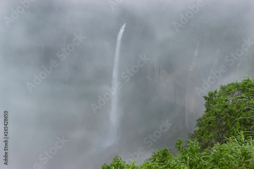 waterfalls falling from a great height rocky mountains overgrown jungles and cloud-covered