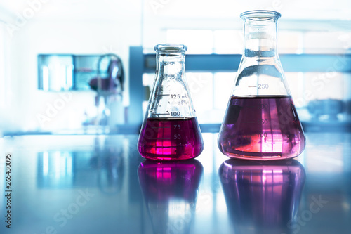 two glass flask with pink solution in chemistry science blue laboratory background