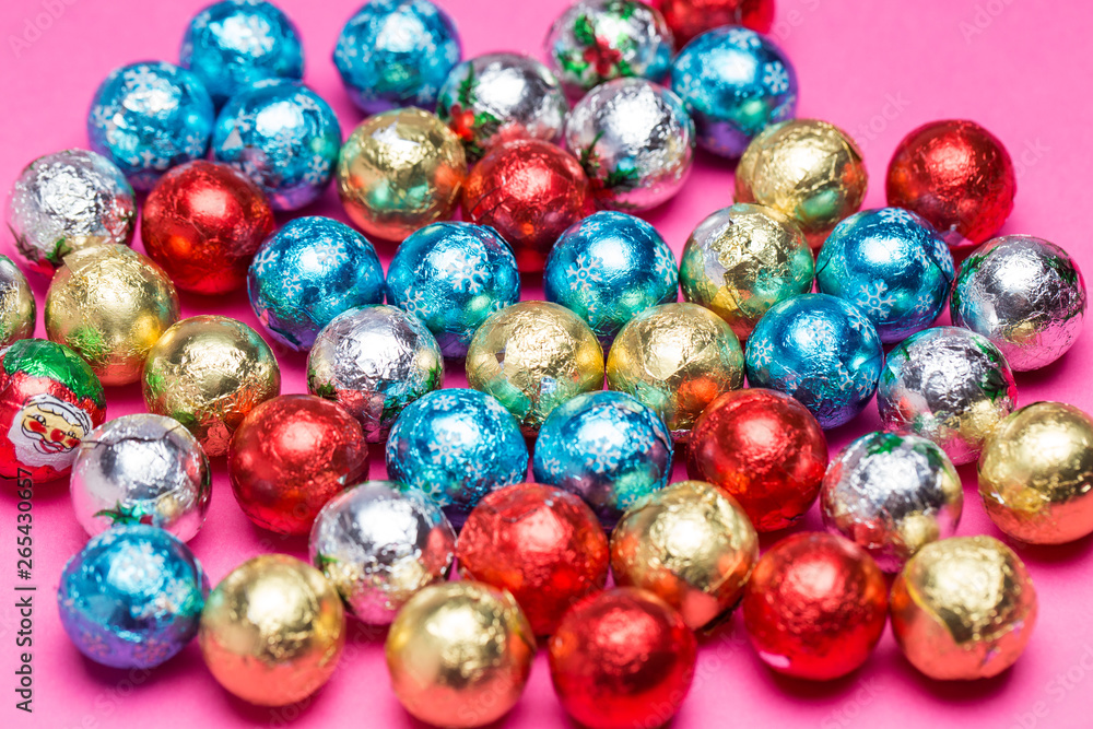 Chocolates in a multi-colored foil on a pink background Chocolates in a multi-colored foil on a pink background