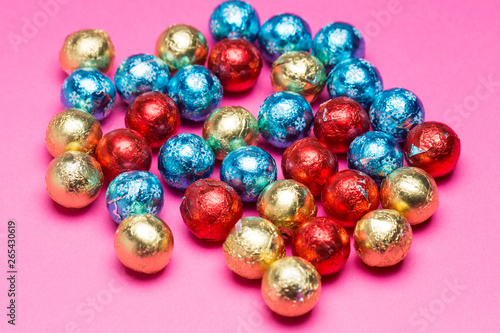 Chocolates in a multi-colored foil on a pink background