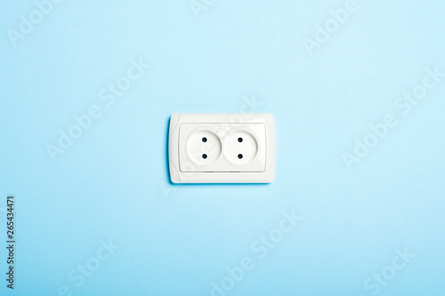 Double white socket on a blue background. Flat lay, top view.