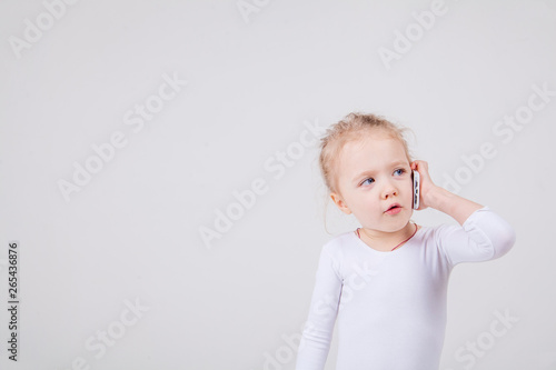 Portrait of the little girl's positive that talking on a cell phone, isolated on white background.