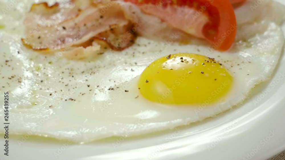 English breakfast. Close-up shot of three fried eggs and bacon serving on a white plate. Slow motion. HD English breakfast. Close-up shot of three fried eggs and bacon serving on a white plate. Slow motion. HD