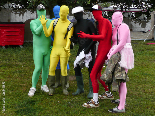 Group of friends at music festival in bright various coloured lycra body suits posing for a photograph having fun.Wearing wellington boots and hats.Image