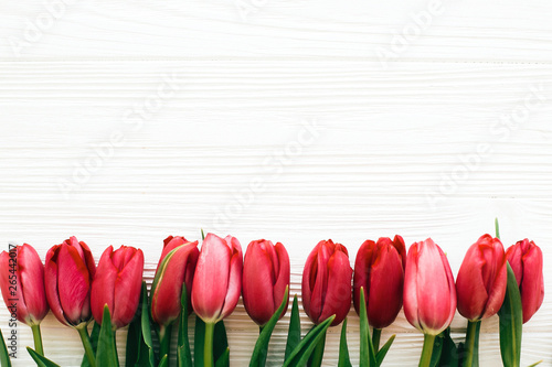 Happy Mothers day. Beautiful red tulips on white wooden background flat lay. Pink tulips border on white wood  border with space for text. Greeting card template. Hello spring concept