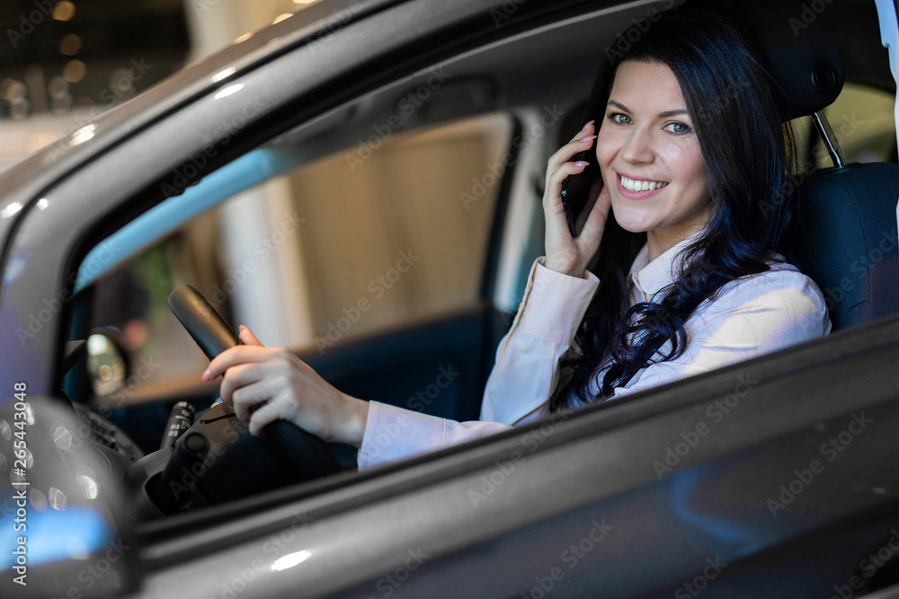 Happy woman buyer sitting in her new vehicle in car dealership