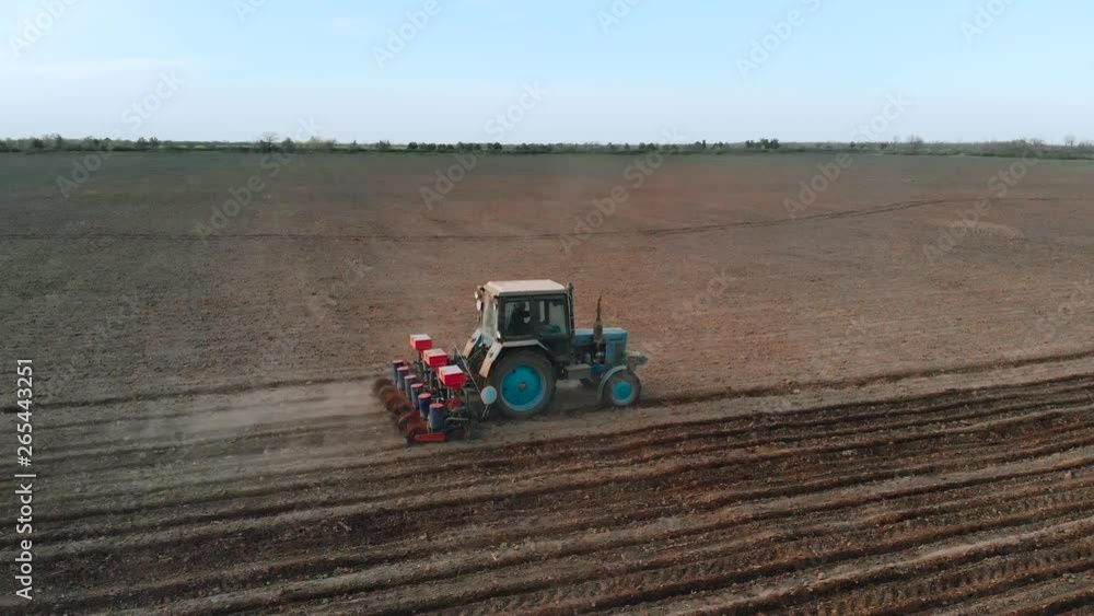 Aerial view on farmer on tractor with six row seeder sow sunflower in field for vegetable oil production. Hard rural job Aerial view on farmer on tractor with six row seeder sow sunflower in field for vegetable oil production. Hard rural job