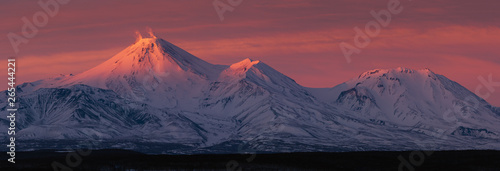 Stunning winter panorama landscape view of volcanoes of Kamchatka Peninsula at sunset: fumarolic activity Avachinsky Volcano (erupting gas, ash) and Kozelsky Volcano. Koryaksky-Avachinsky Group of Vol photo