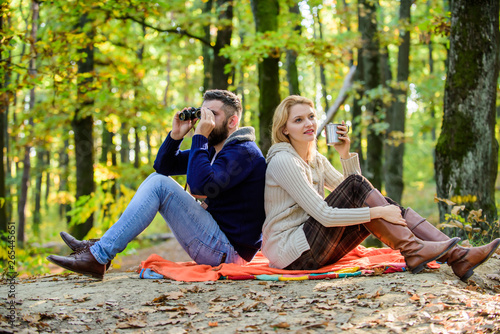 Relaxing in park together. Happy loving couple relaxing in park together. Couple in love tourists relaxing picnic blanket. Man with binoculars and woman with metal mug enjoy nature park. Park date