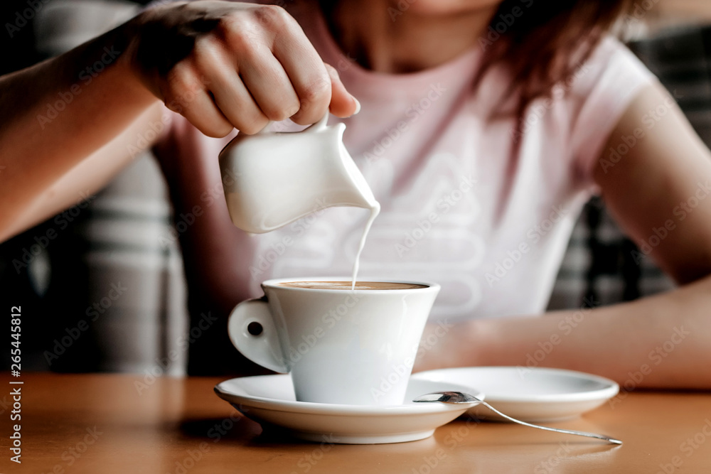 Morning coffee. Closeup of women's hands with coffee cup in a cafe. Female hands holding cups of coffee on a wooden table background in a cafe, vintage color tone Morning coffee. Closeup of women's hands with coffee cup in a cafe. Female hands holding cups of coffee on a wooden table background in a cafe, vintage color tone