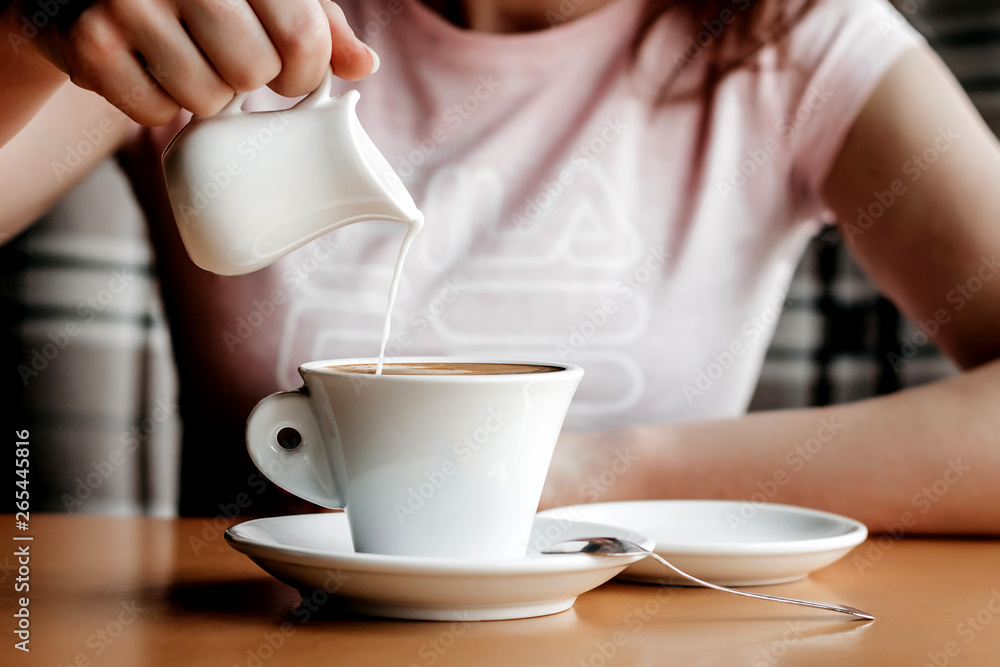 Morning coffee. Closeup of women's hands with coffee cup in a cafe. Female hands holding cups of coffee on a wooden table background in a cafe, vintage color tone Morning coffee. Closeup of women's hands with coffee cup in a cafe. Female hands holding cups of coffee on a wooden table background in a cafe, vintage color tone