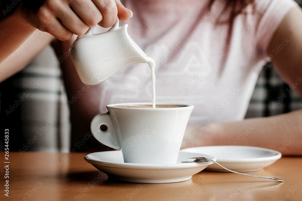 Morning coffee. Closeup of women's hands with coffee cup in a cafe. Female hands holding cups of coffee on a wooden table background in a cafe, vintage color tone Morning coffee. Closeup of women's hands with coffee cup in a cafe. Female hands holding cups of coffee on a wooden table background in a cafe, vintage color tone
