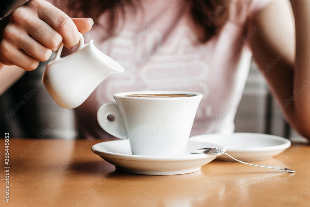 Morning coffee. Closeup of women's hands with coffee cup in a cafe. Female hands holding cups of coffee on a wooden table background in a cafe, vintage color tone Morning coffee. Closeup of women's hands with coffee cup in a cafe. Female hands holding cups of coffee on a wooden table background in a cafe, vintage color tone