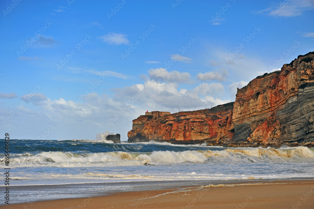 Beautiful beach of Nazare with lighthouse on cliffs